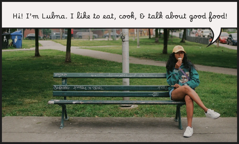 Lubna sitting cross-legged on a graffiti-ed bench in a city park eating an ice cream cone. Text on the top of the photo in the style of a comic book speech bubble reads "Hi! I'm Lubna. I like to eat, cook, & talk about good food!"